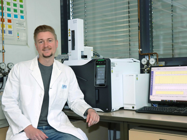 Ein Chemiker sitzt vor einem Gaschromatographen mit Massenspektrometer (GC-MS)