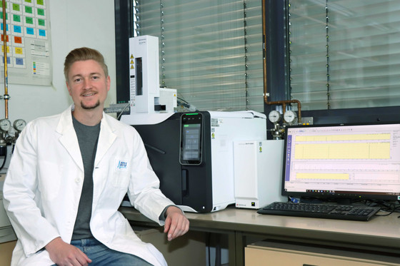 Ein Chemiker sitzt vor einem Gaschromatographen mit Massenspektrometer (GC-MS)